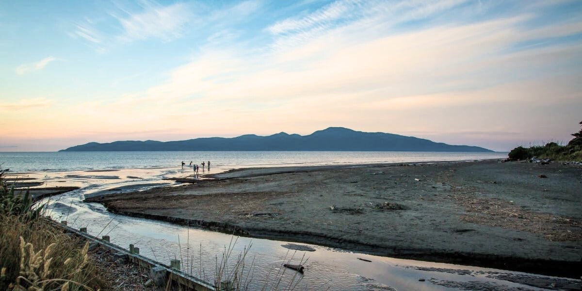 Waikanae beach with a stream running through it and Kapiti Island in the background